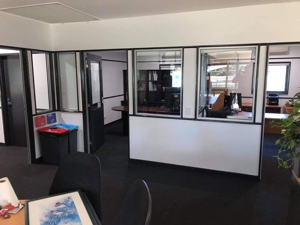 An Empty Office With Black Carpet And Large Windows After Renovation — Entire Trades in Port Stephens, NSW