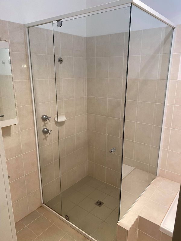 A Modern Bathroom Featuring A Glass Shower Door Alongside A Glass Door And A Toilet For A Sleek — Entire Trades in Port Stephens, NSW