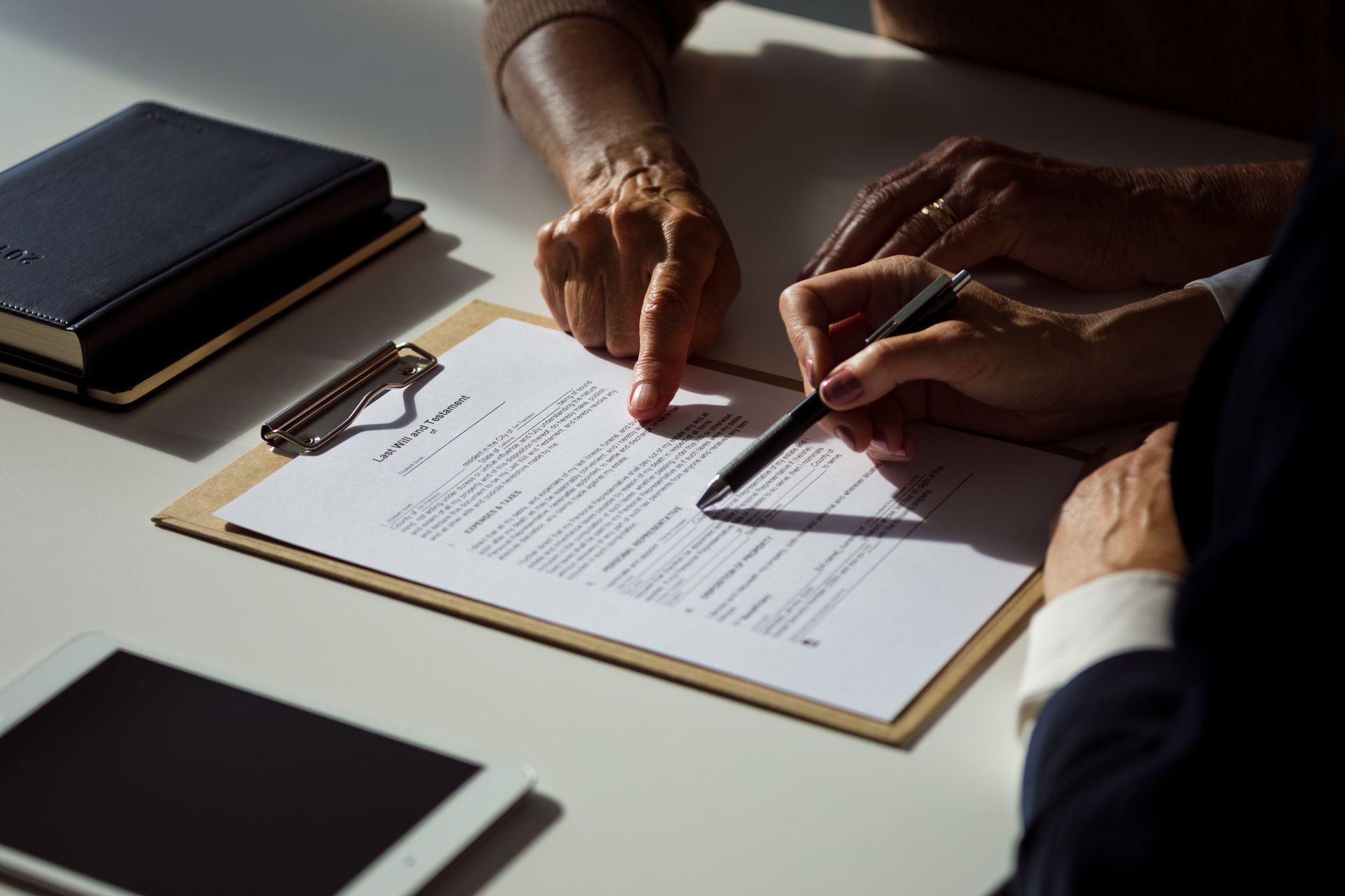 Close-up of hands from a lawyer explaining a will to their client.