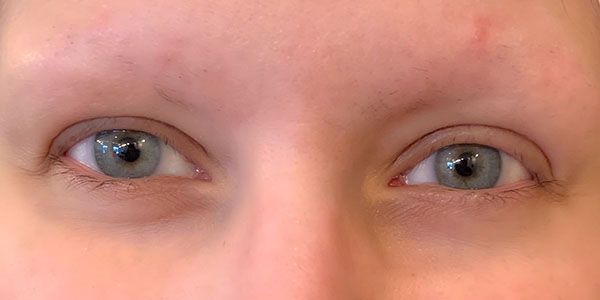 A close up of a woman 's blue eyes without makeup.
