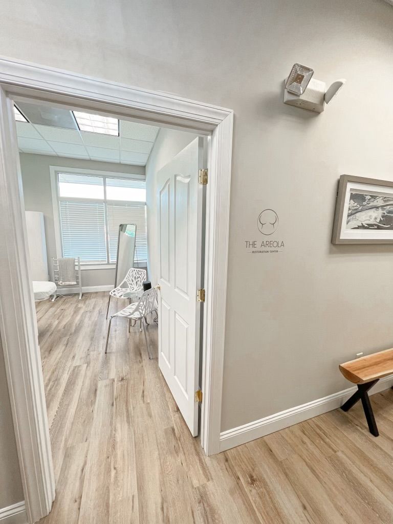 A white door is open to a room with wooden floors and a bench.