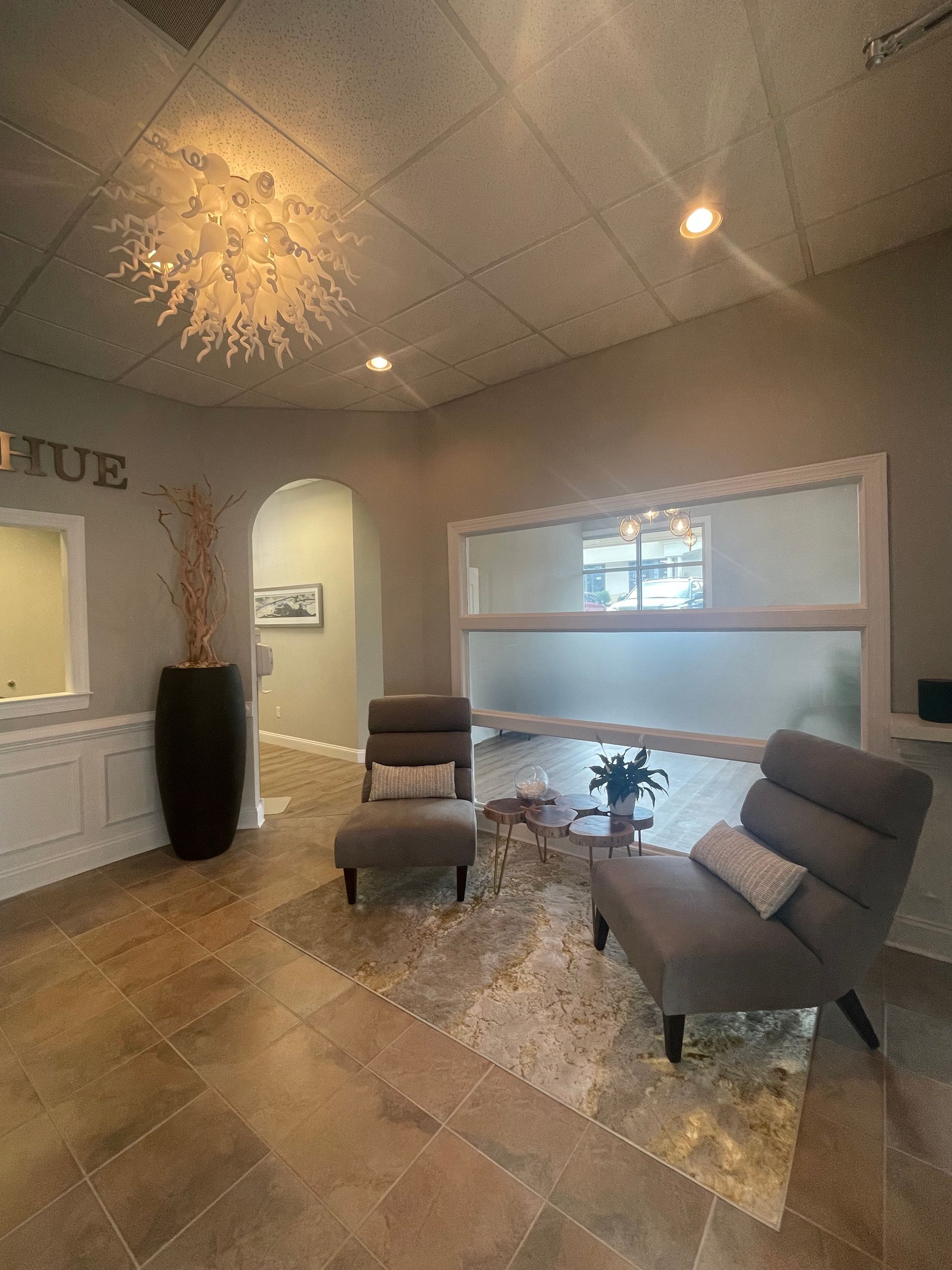 A living room with chairs , a table and a chandelier.
