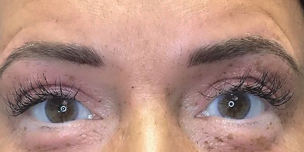 A close up of a woman 's eyes with long eyelashes and freckles.