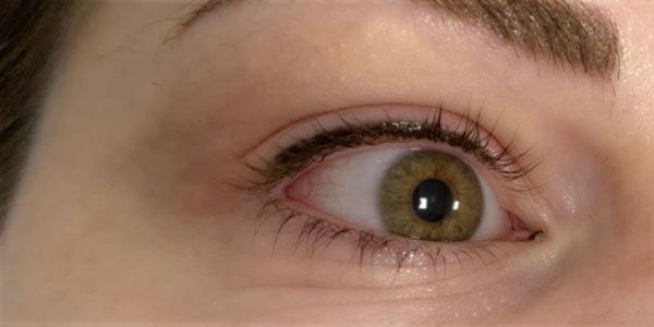 A close up of a woman 's green eye with long eyelashes.