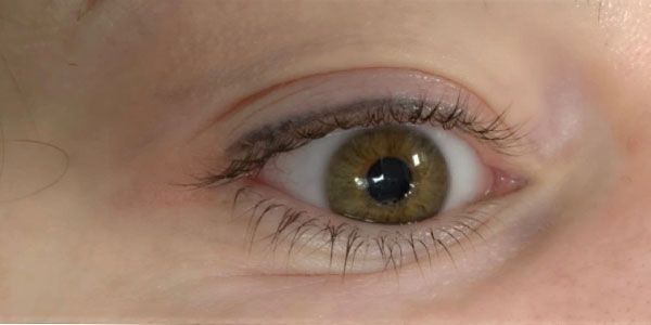A close up of a woman 's green eye with long eyelashes.