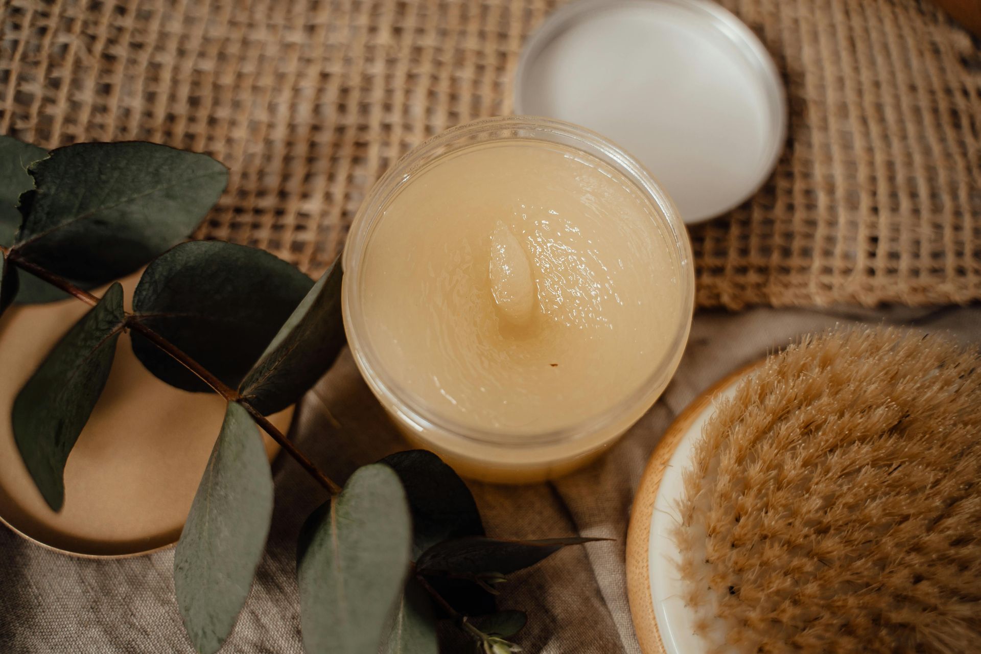 Candles, eucalyptus leaves, and a round brush on burlap background