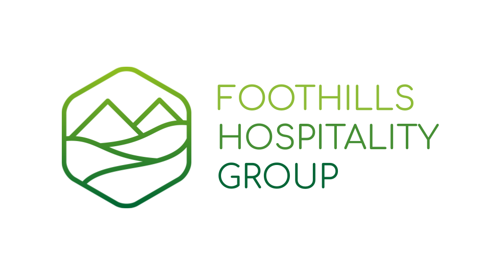 The logo for foothills hospitality group is a green hexagon with mountains in it.
