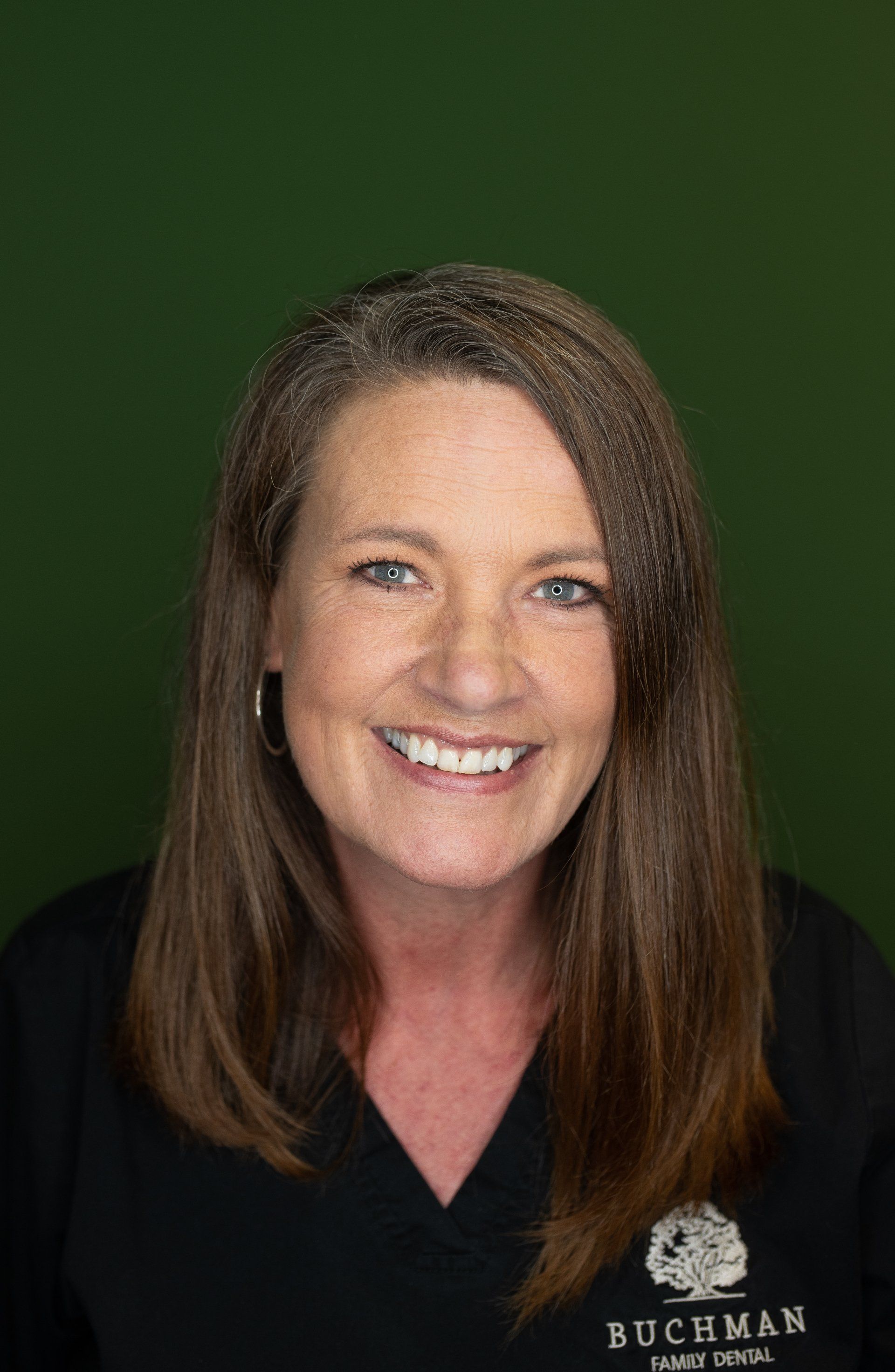A woman in a black scrub top is smiling for the camera.
