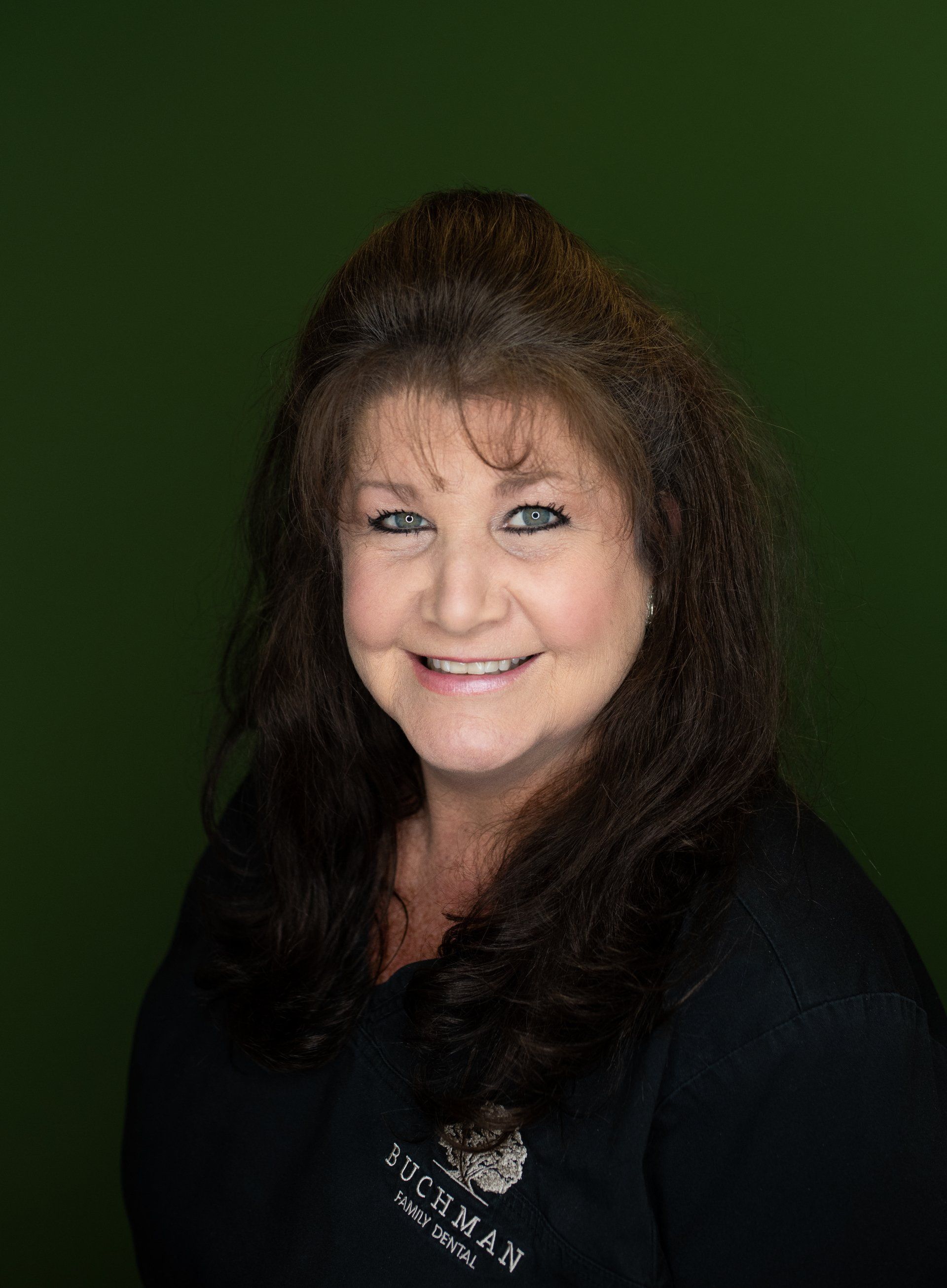 A woman with long hair and blue eyes is smiling for the camera.