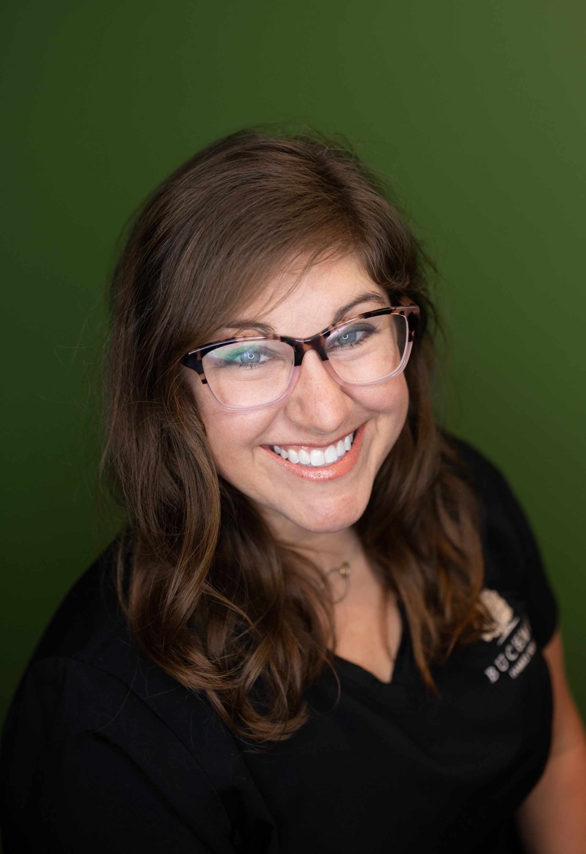 A woman wearing glasses and a black shirt is smiling for the camera.