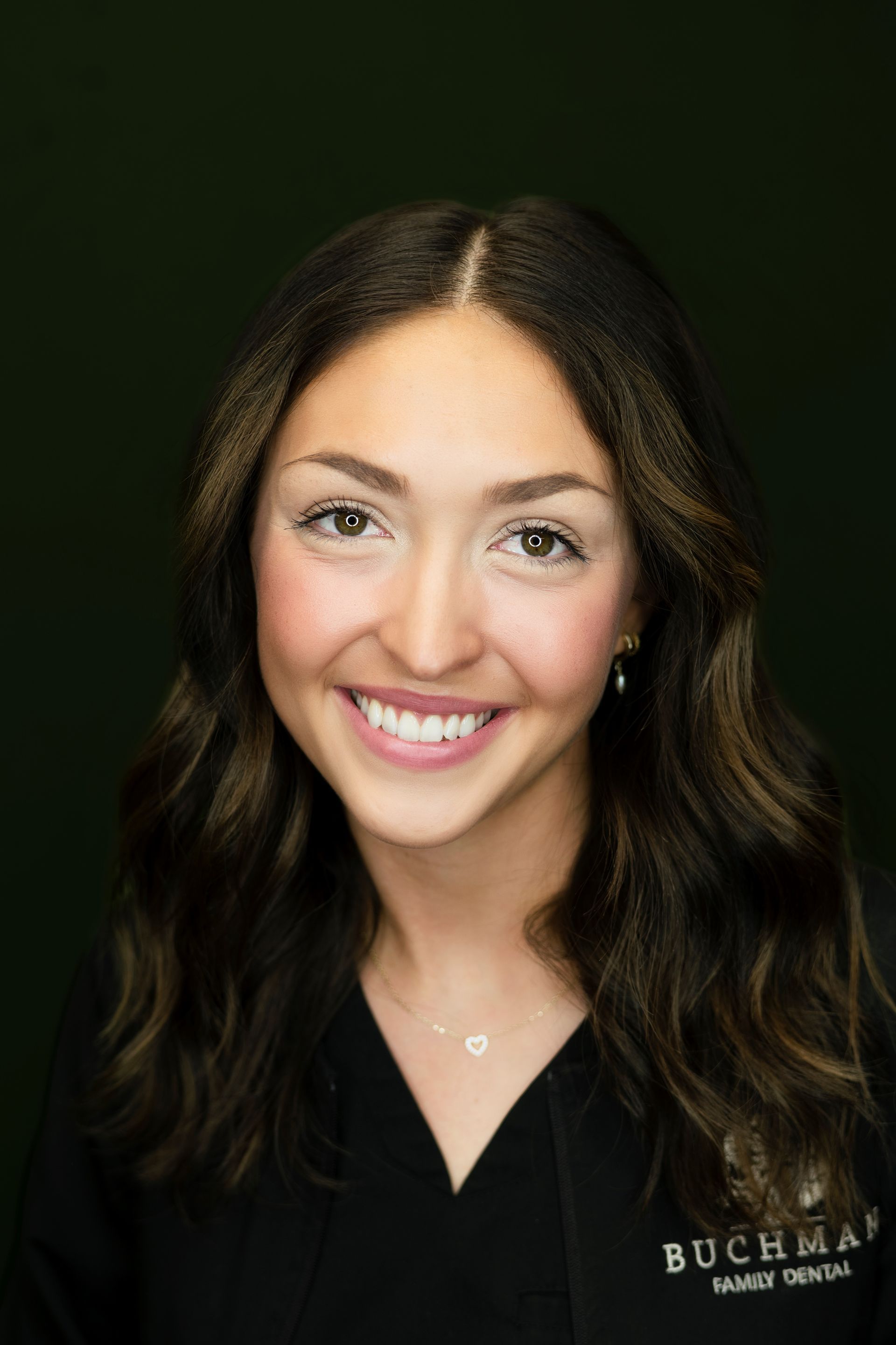 A woman in a black scrub top is smiling for the camera.