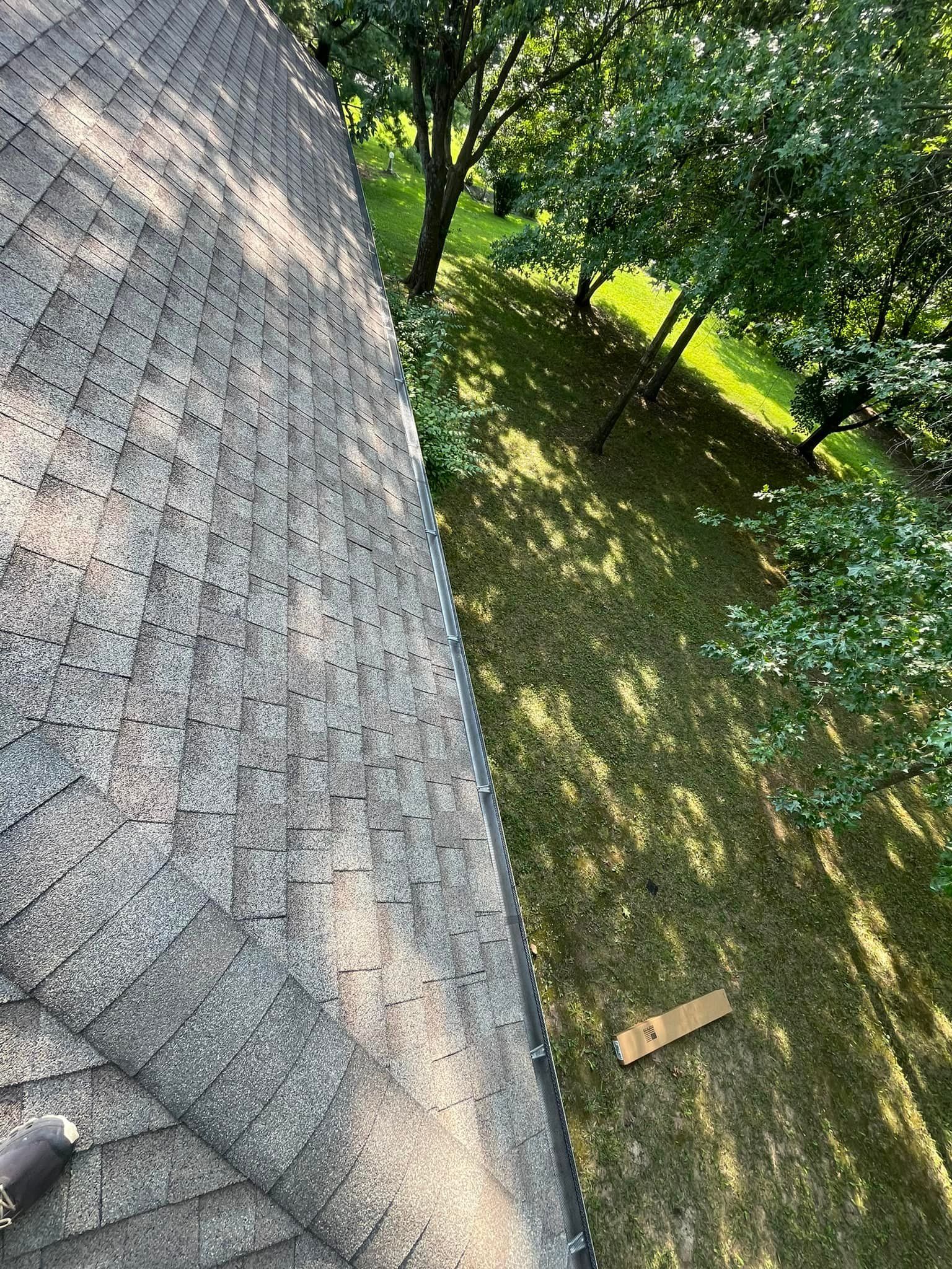 An aerial view of a roof with a gutter and trees in the background.