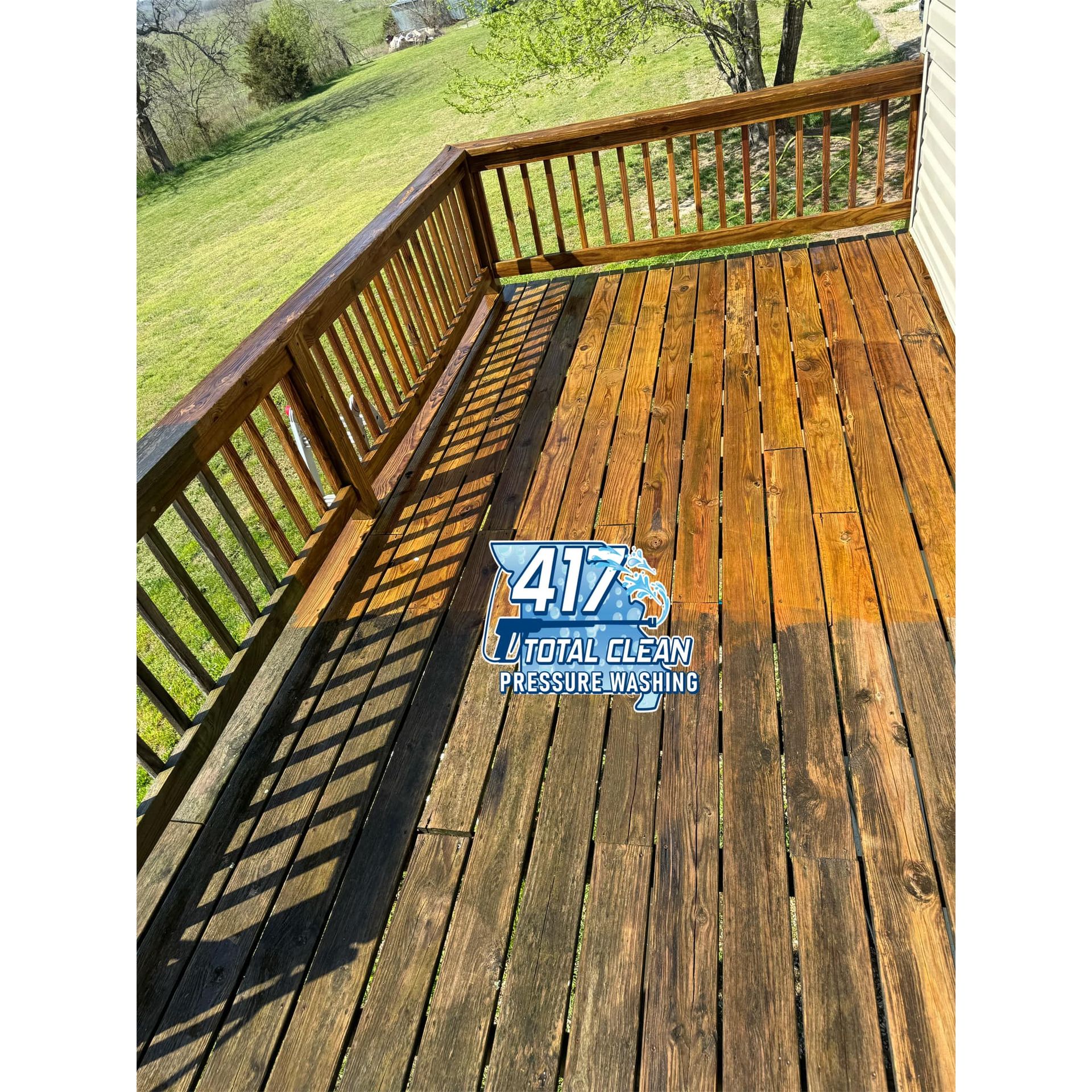 A wooden deck with a railing and a lawn in the background.