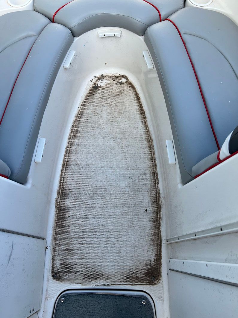 The back of a boat with a dirty seat and a dirty floor.