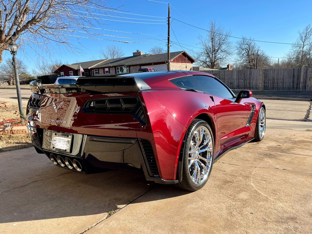A red sports car is parked in a driveway in front of a house.