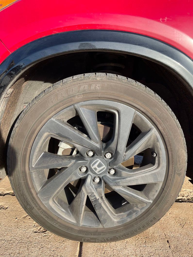 A close up of a red honda cr v wheel and tire.