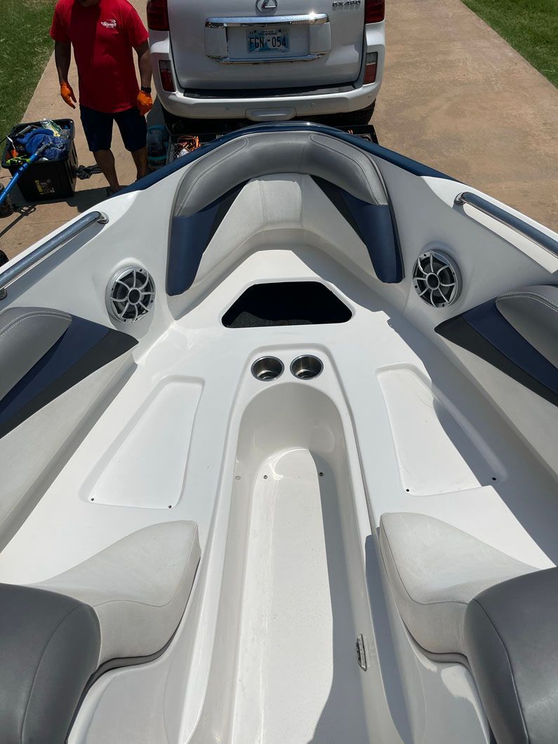 A man is standing next to a boat in a driveway
