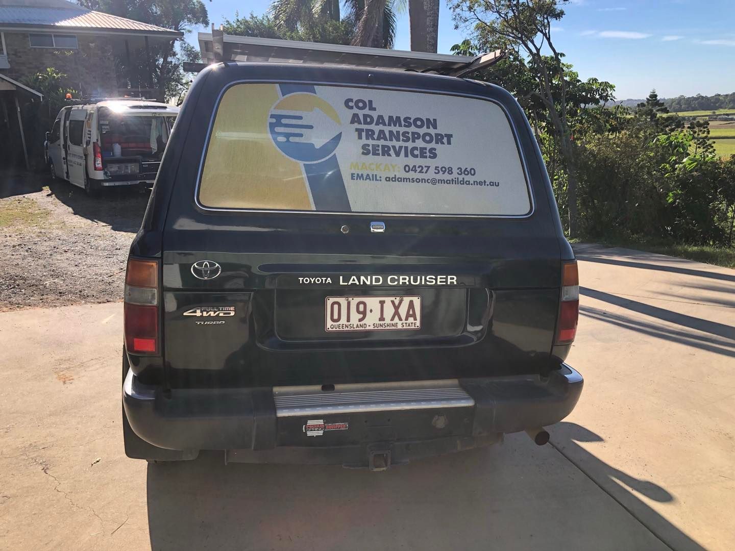 Black Toyota Land Cruiser with business logo on rear window. License plate reads 019-IXA — Col Adamson Transport Services in Farleigh, QLD