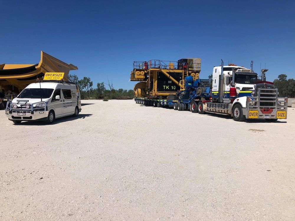 Semi-truck Hauling Large Yellow Industrial Equipment on a Gravel Lot — Col Adamson Transport Services in Townsville, QLD