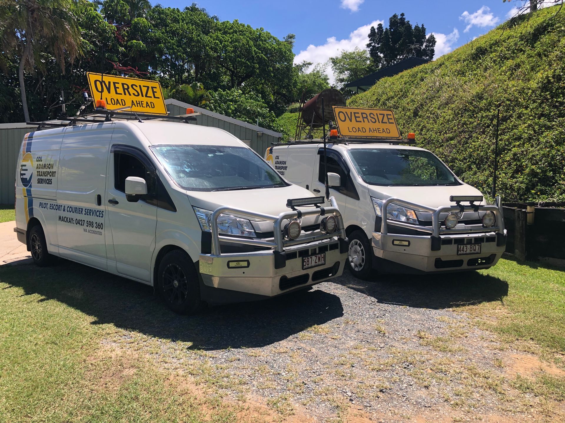 Two White Vans with Signs Parked Outdoors — Col Adamson Transport Services in Rockhampton, QLD