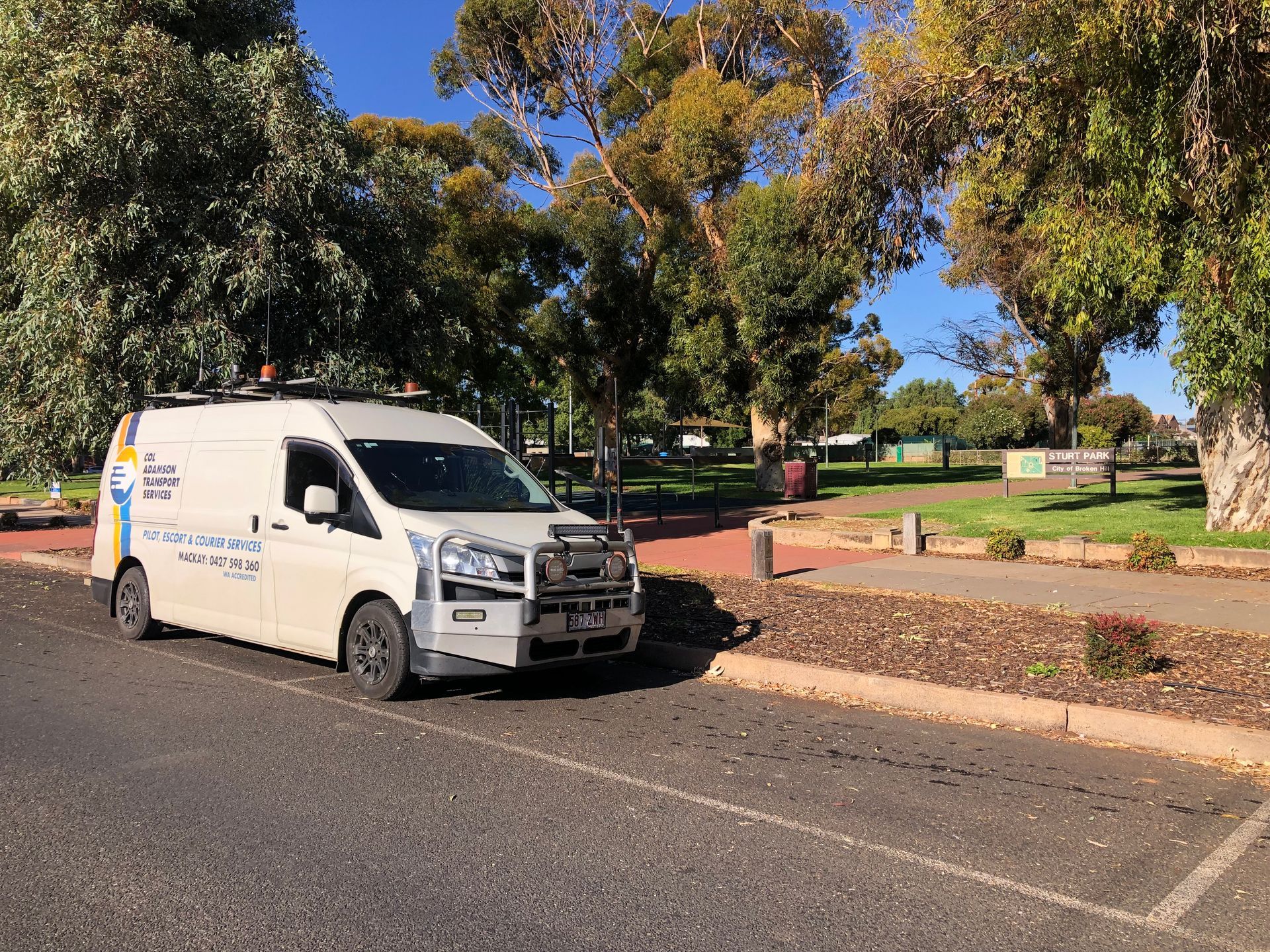 White Service Van Parked on Street Next to A Park — Col Adamson Transport Services in Moranbah, QLD