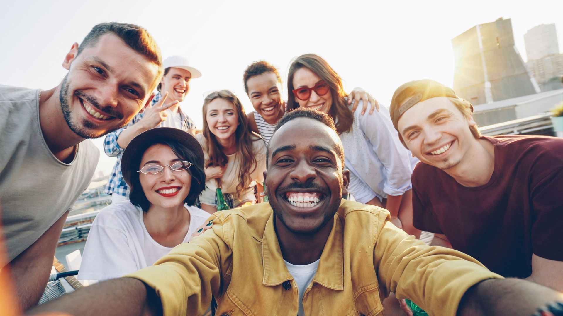 Smiling group selfie outdoors with a city skyline in the background