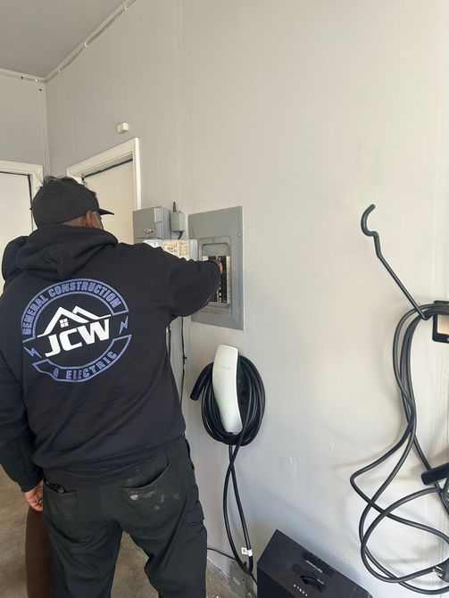 Worker installing equipment on a wall beside hanging cables in a utility room