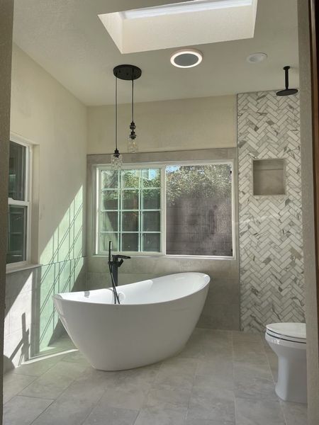 Modern bathroom with freestanding tub, walk-in shower, and skylight lighting.