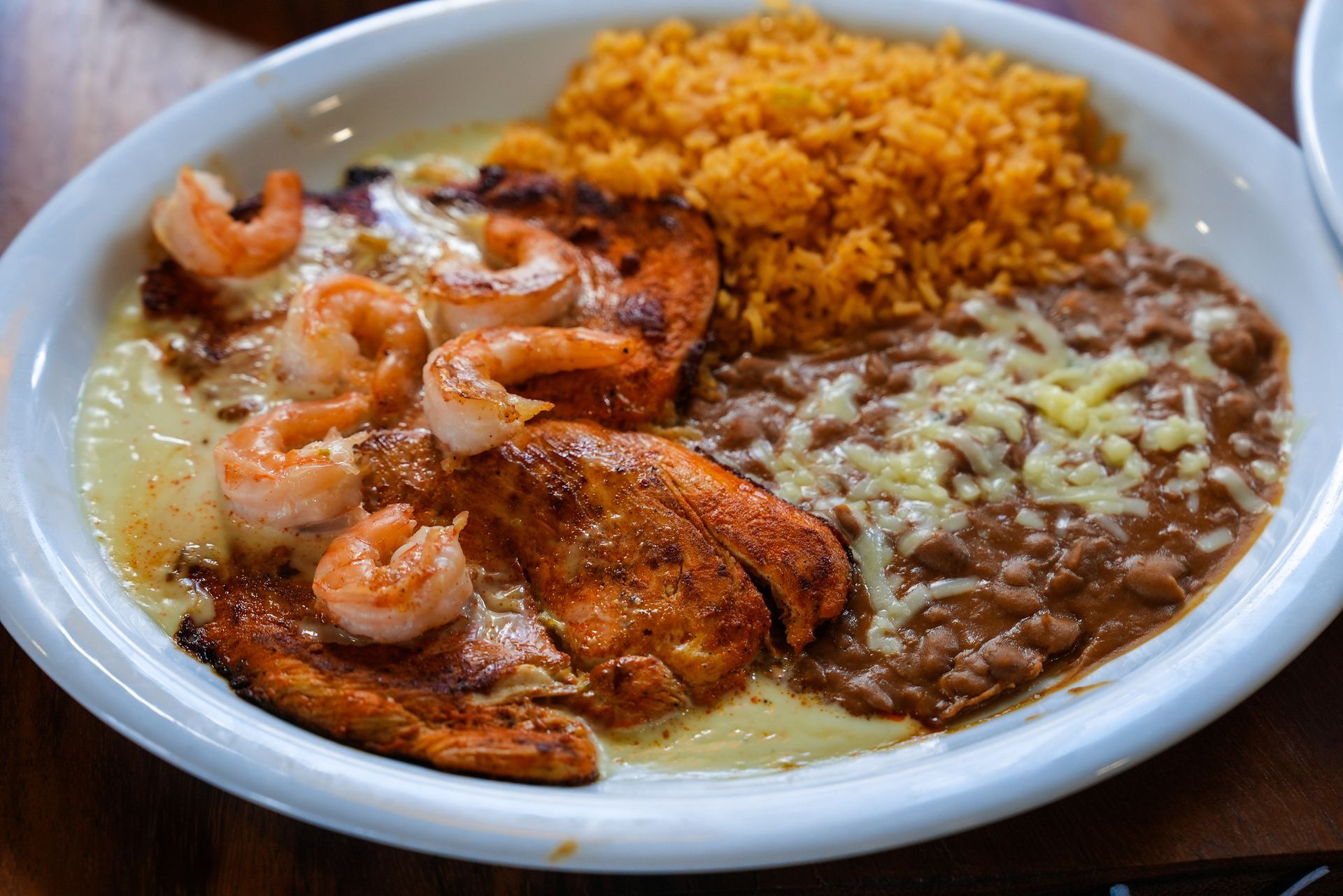 A white plate topped with shrimp rice and beans