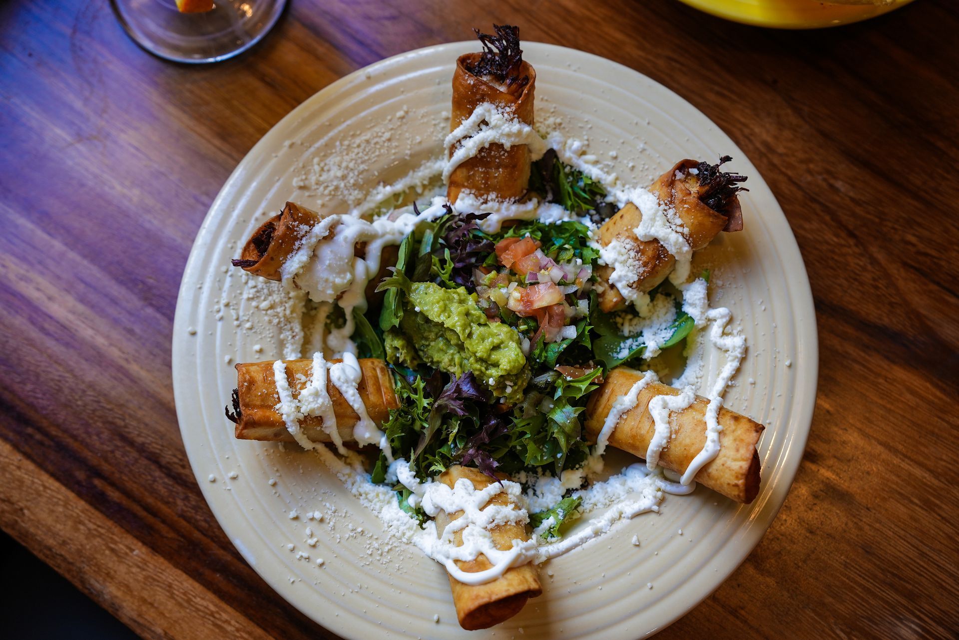 A plate of food with guacamole and sour cream on a wooden table