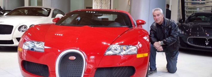 Red sports car in a showroom with a person kneeling beside it.