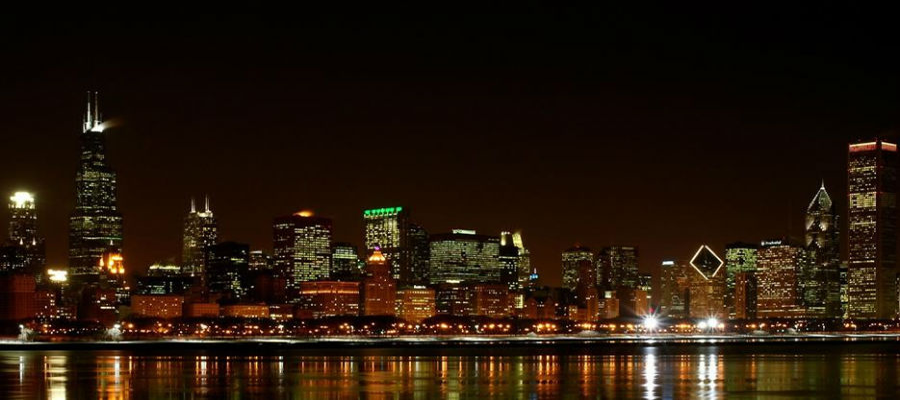 Nighttime city skyline with illuminated skyscrapers reflected on calm water