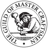 Circular black-and-white seal reading “THE GUILD OF MASTER CRAFTSMAN,” with a craftsman hammering at a bench.