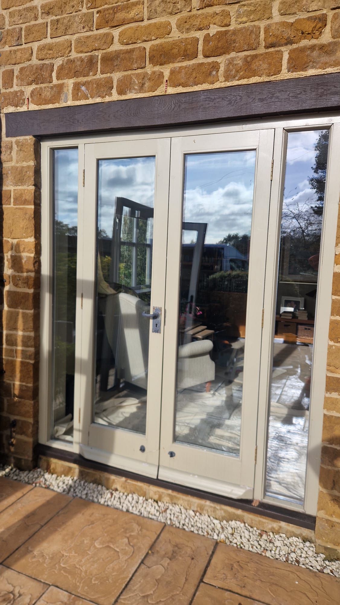White double doors in a brick wall reflecting an outdoor patio and sky