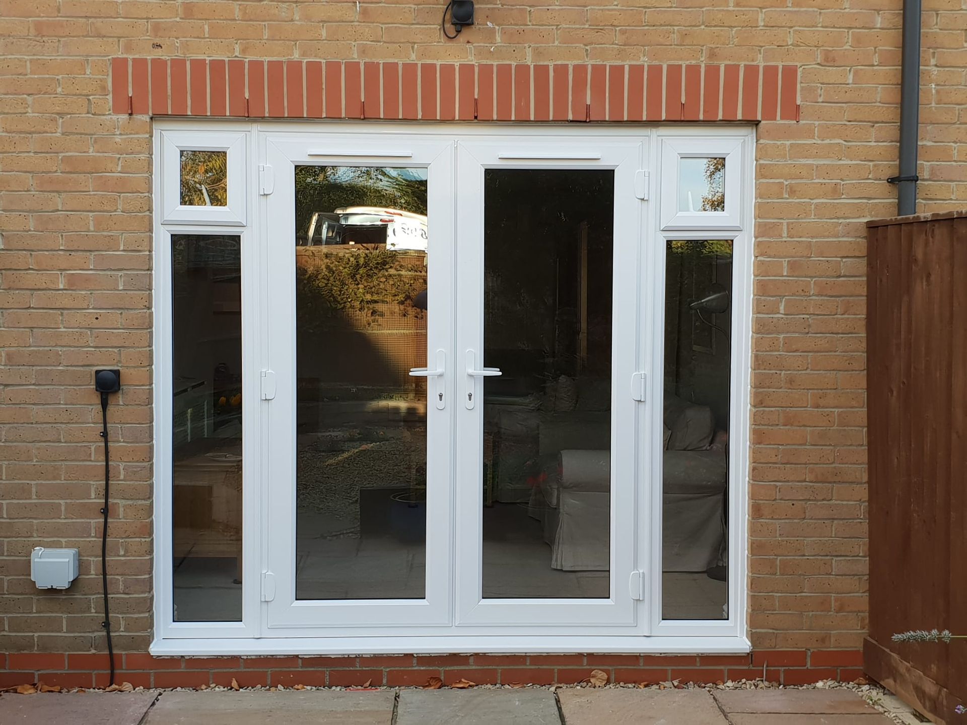 White double patio doors set in a brick wall with narrow side windows.