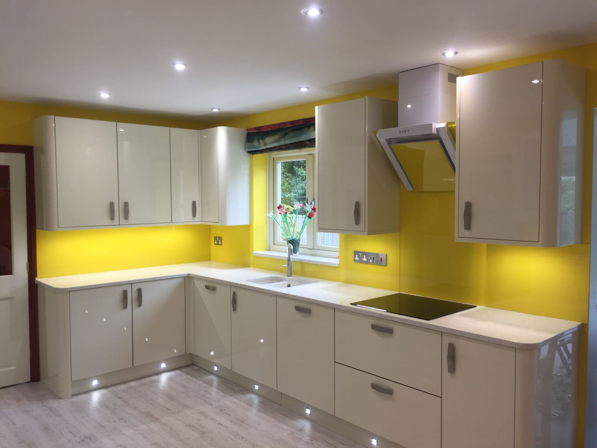 Modern kitchen with cream cabinets, bright yellow backsplash, and a window over the sink