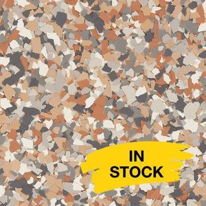 A speckled epoxy floor coating featuring a mix of tan, brown, dark grey, and white flakes with a yellow 