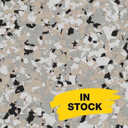 Close-up of a multi-colored stone or epoxy flake flooring texture in shades of tan, grey, white, and black with 