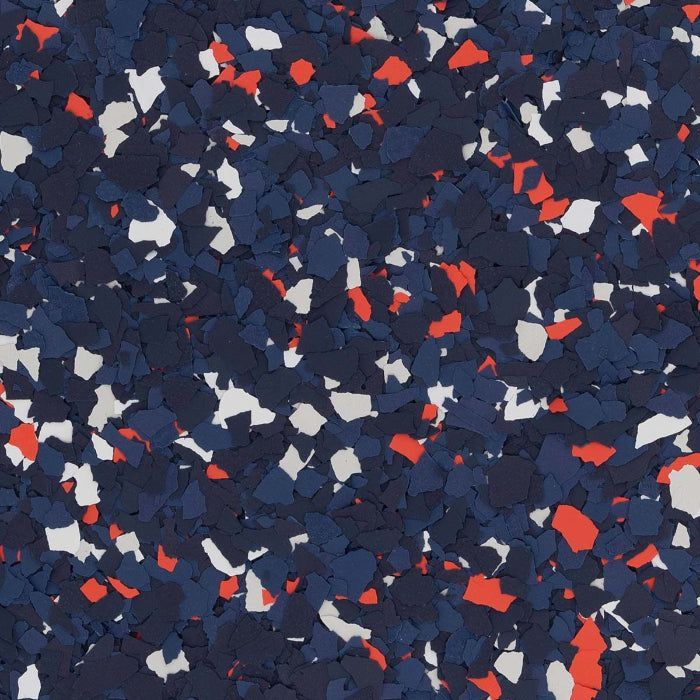 A close-up view of decorative floor flakes in a mix of dark blue, light blue, white, and red.