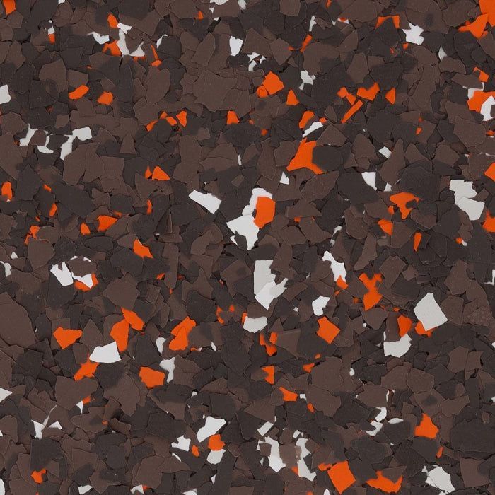 A close-up of decorative floor flakes in a mix of brown, white, and orange pieces scattered across a dark background.