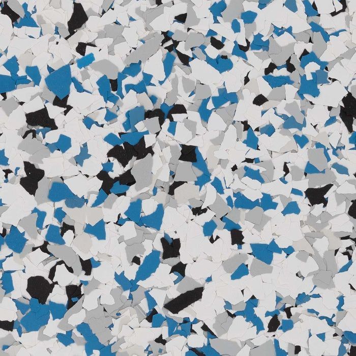 A close-up of decorative floor flakes in a pattern of white, grey, blue, and black chips.