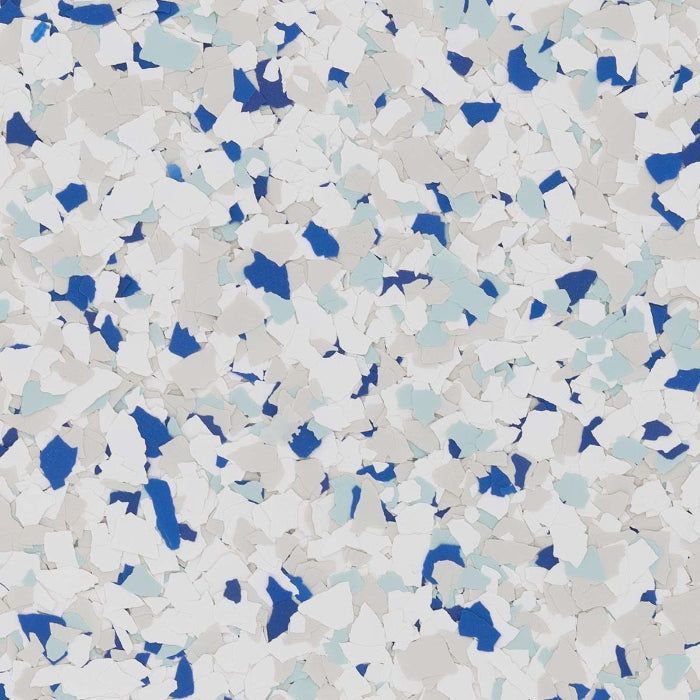 A close-up of a decorative epoxy floor finish with a speckled pattern of white, gray, light blue, and dark blue flakes.