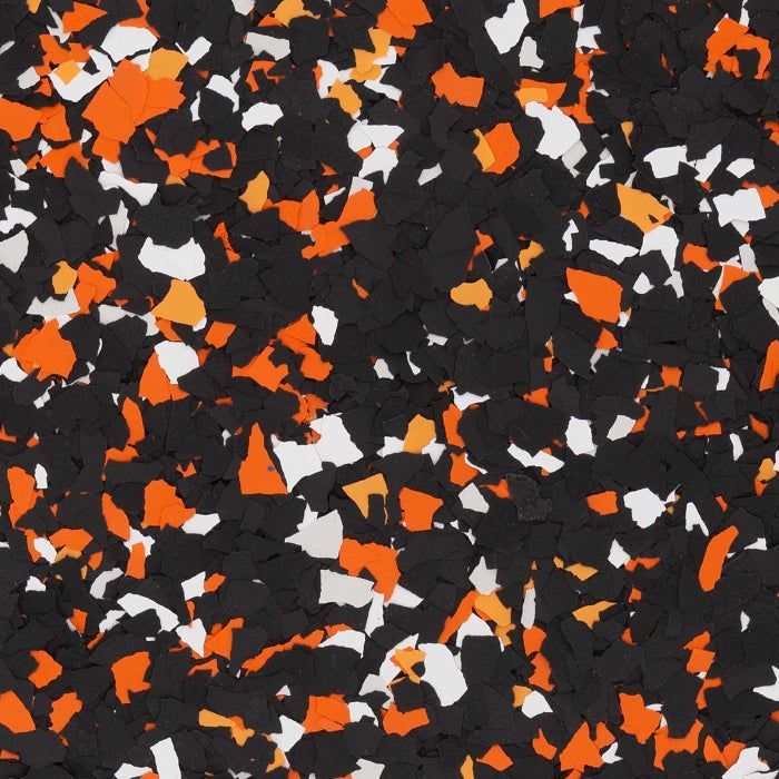 A close-up of decorative epoxy floor flakes in a random mix of black, bright orange, and white chips.
