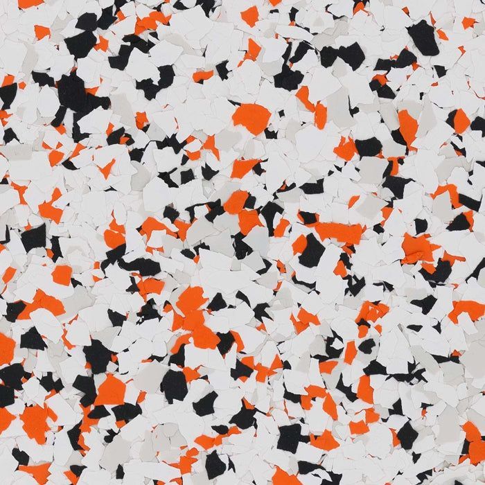 A close-up of a decorative flooring finish featuring a dense blend of white, light gray, black, and bright orange chips.