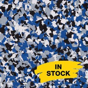 A close-up of blue, white, black, and gray paint chips used for epoxy flooring, with a yellow 