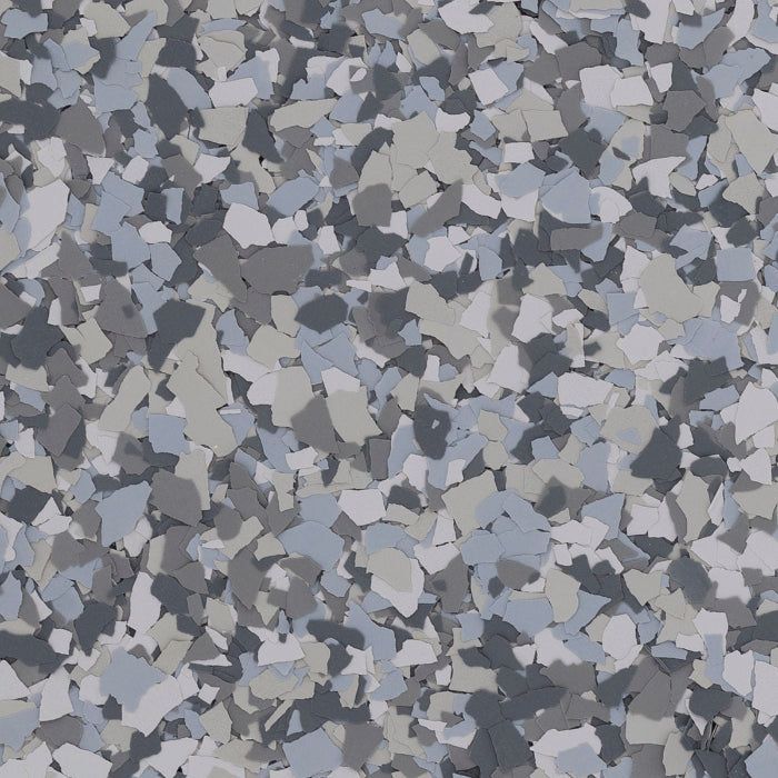 A close-up of multi-colored grey, blue, and white paint flakes used for decorative epoxy floor coating.