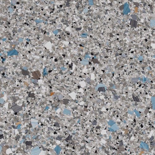 A close-up of gray decorative flooring flakes featuring a speckled mix of blue, black, white, and tan pieces.