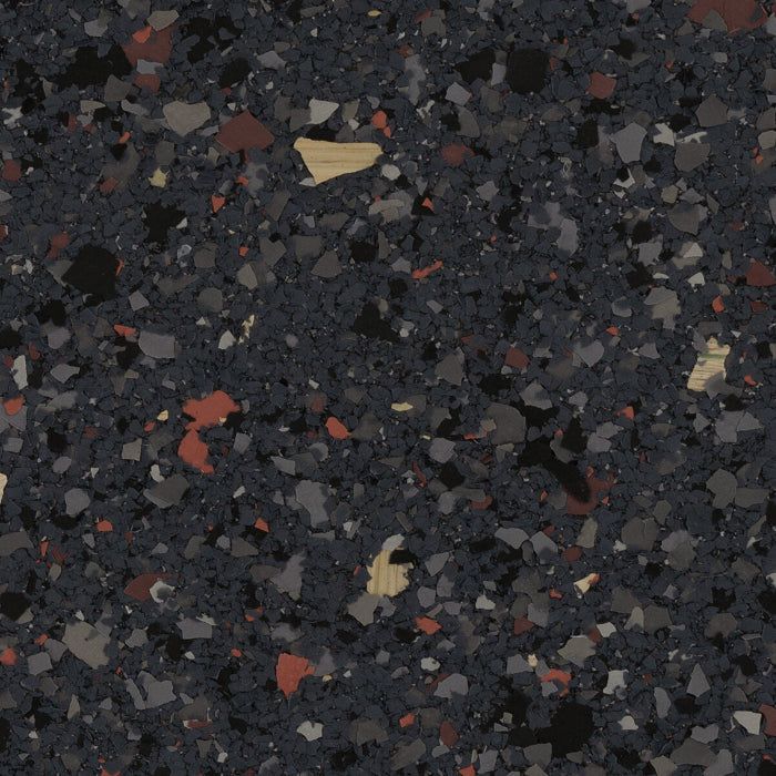 Textured flooring material featuring a dark gray speckled pattern with small accents of red, white, and black flakes.