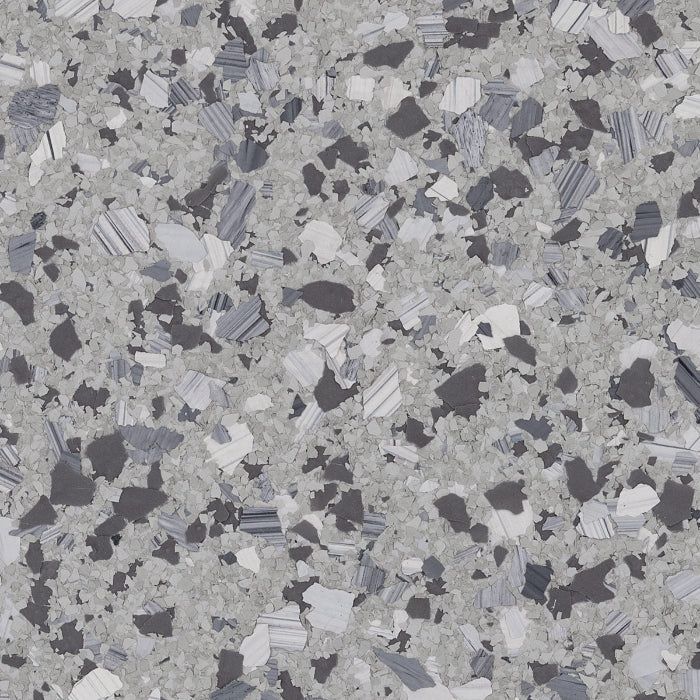 A close-up of light gray, speckled epoxy flooring with dark gray and white paint flakes.
