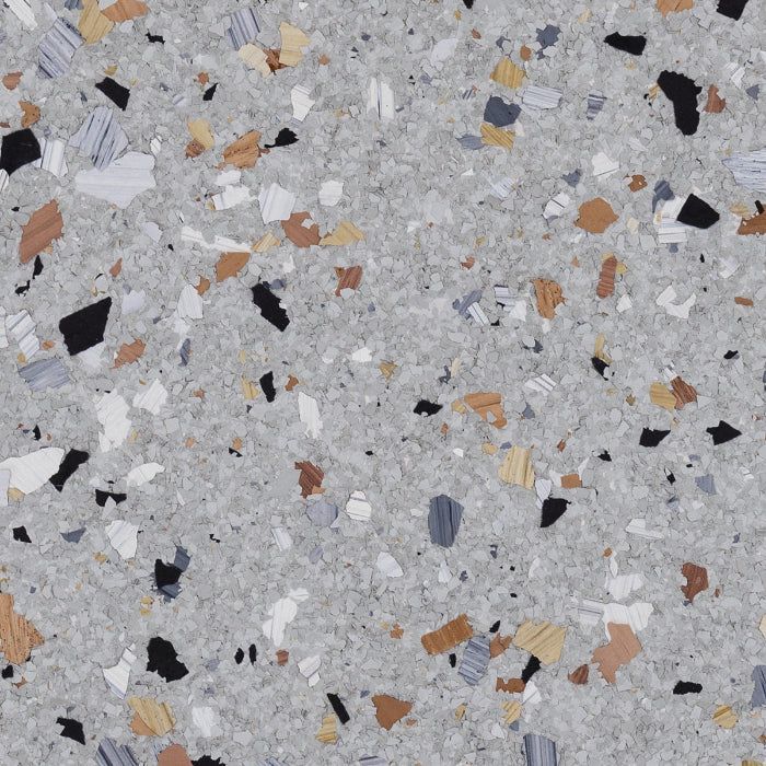 A close-up of a speckled floor coating with grey, white, black, and tan flecks on a light grey, textured background.